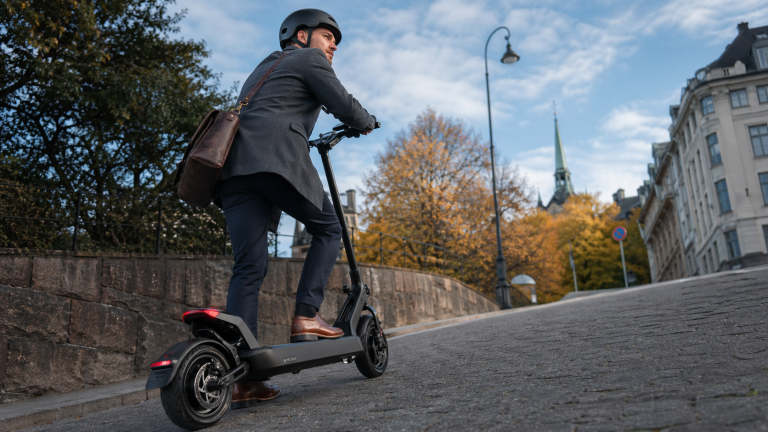 En mann på elsparkesykkel i en norsk gate